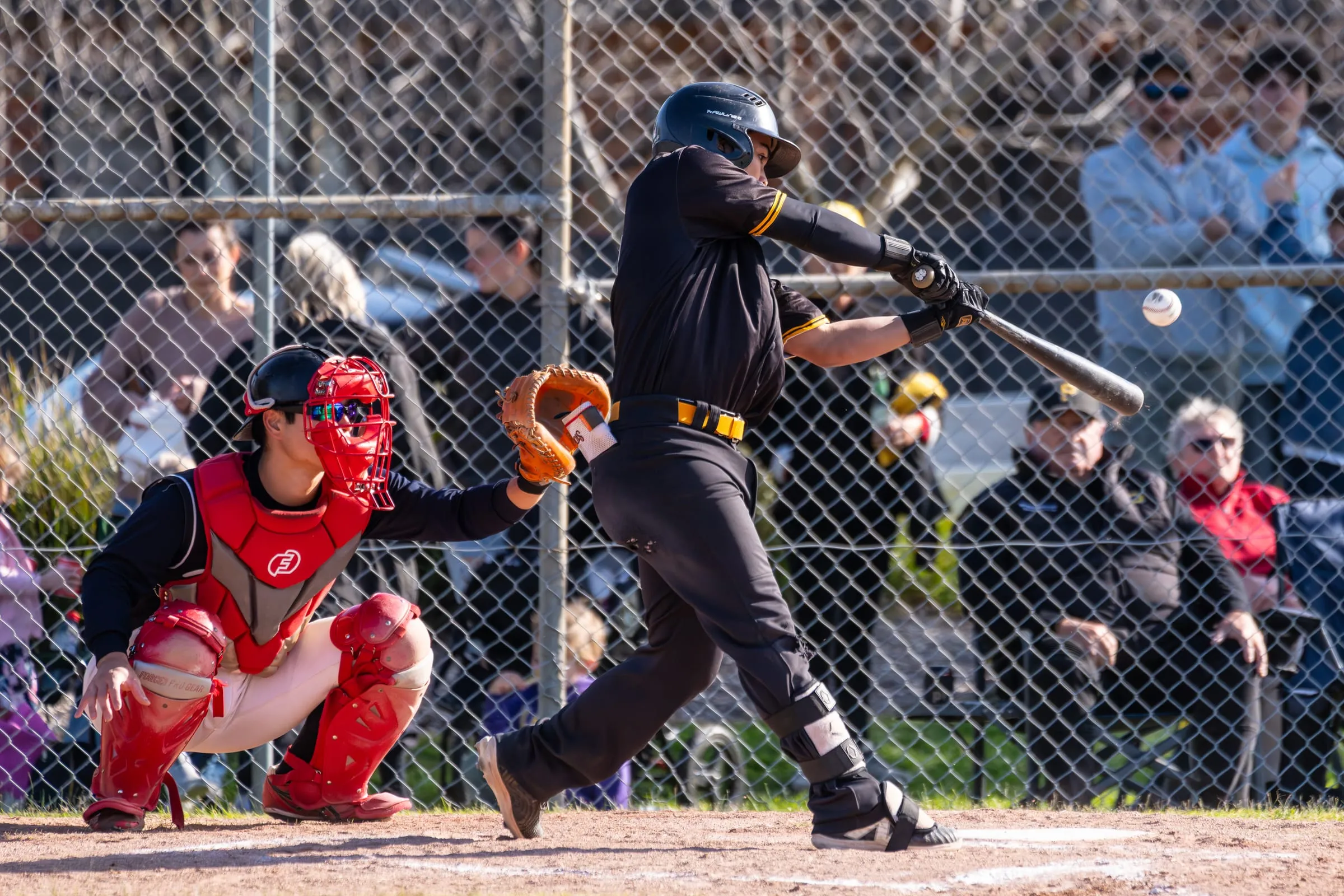 A Pirates batter swings in front of the catcher and a packed crowd