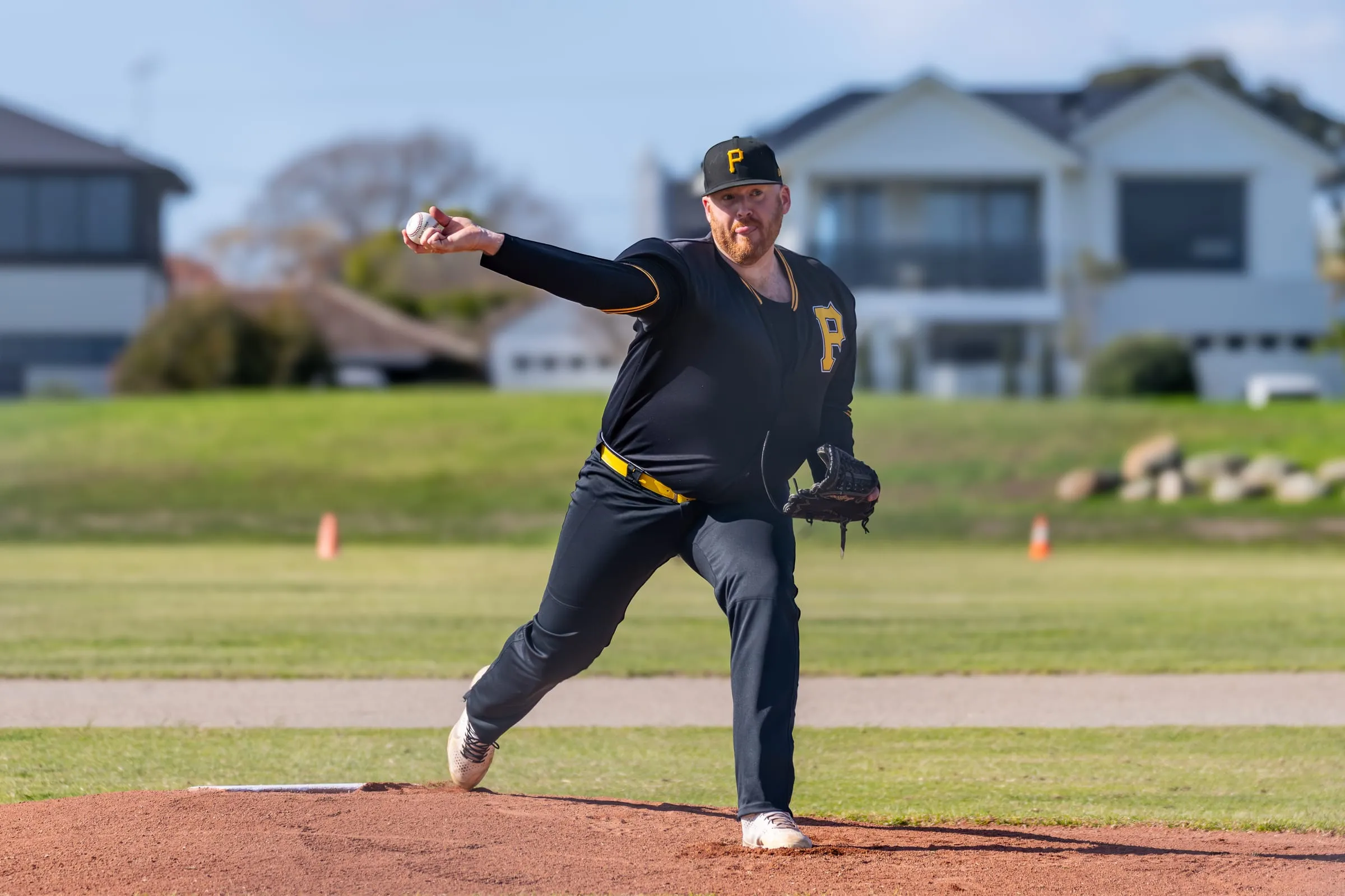 A Pirates pitcher in black and gold follows through after a pitch
